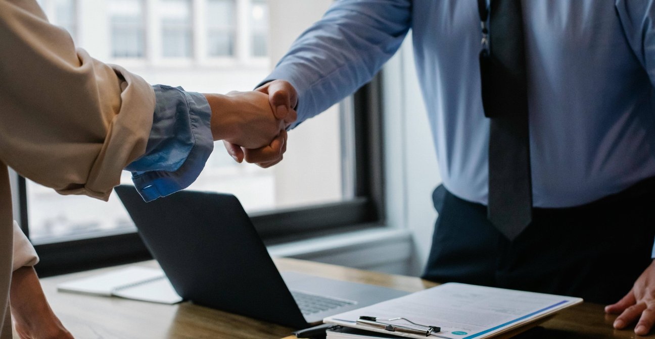 Muž v košili a kravatě podávající ruku klientovi